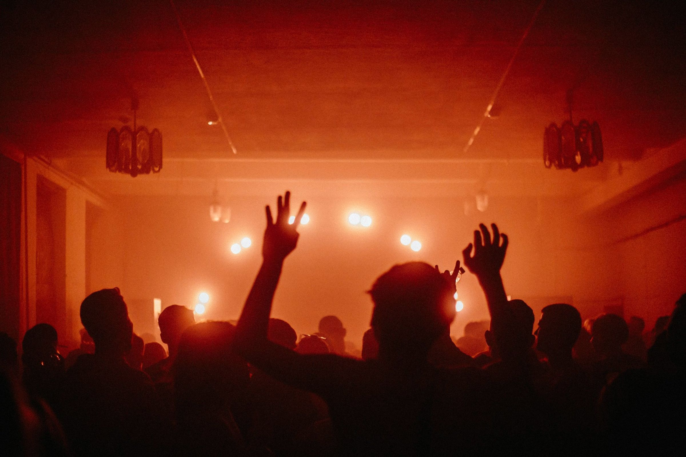 A crowd with hands raised under warm stage lights